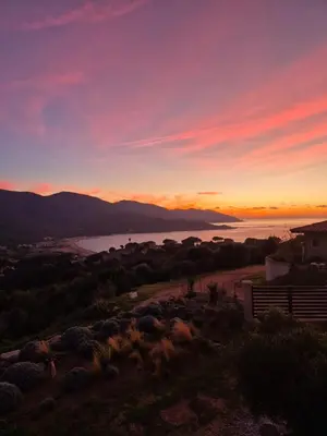 a sunset over a body of water with a house at Vue de rêve in Calcatoggio