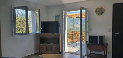 a living room with a tv and a sliding glass door at Vue de rêve in Calcatoggio
