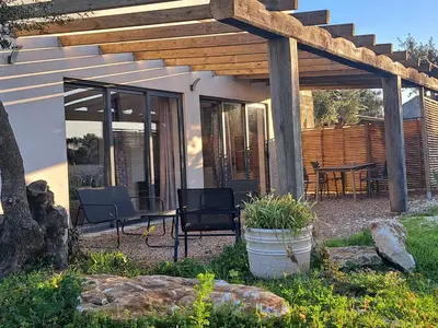 a patio with a table and chairs under a wooden pergola at Maison au calme idéalement située proche plage in Bonifacio