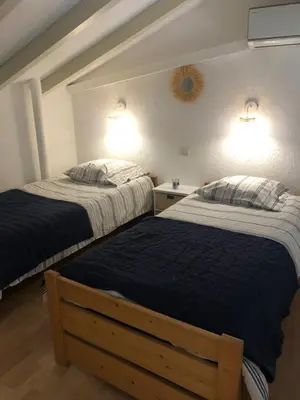 two beds in a bedroom with two lamps on the wall at Altura in Zonza
