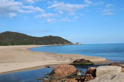 a beach with rocks and the ocean on a sunny day at Altura in Zonza